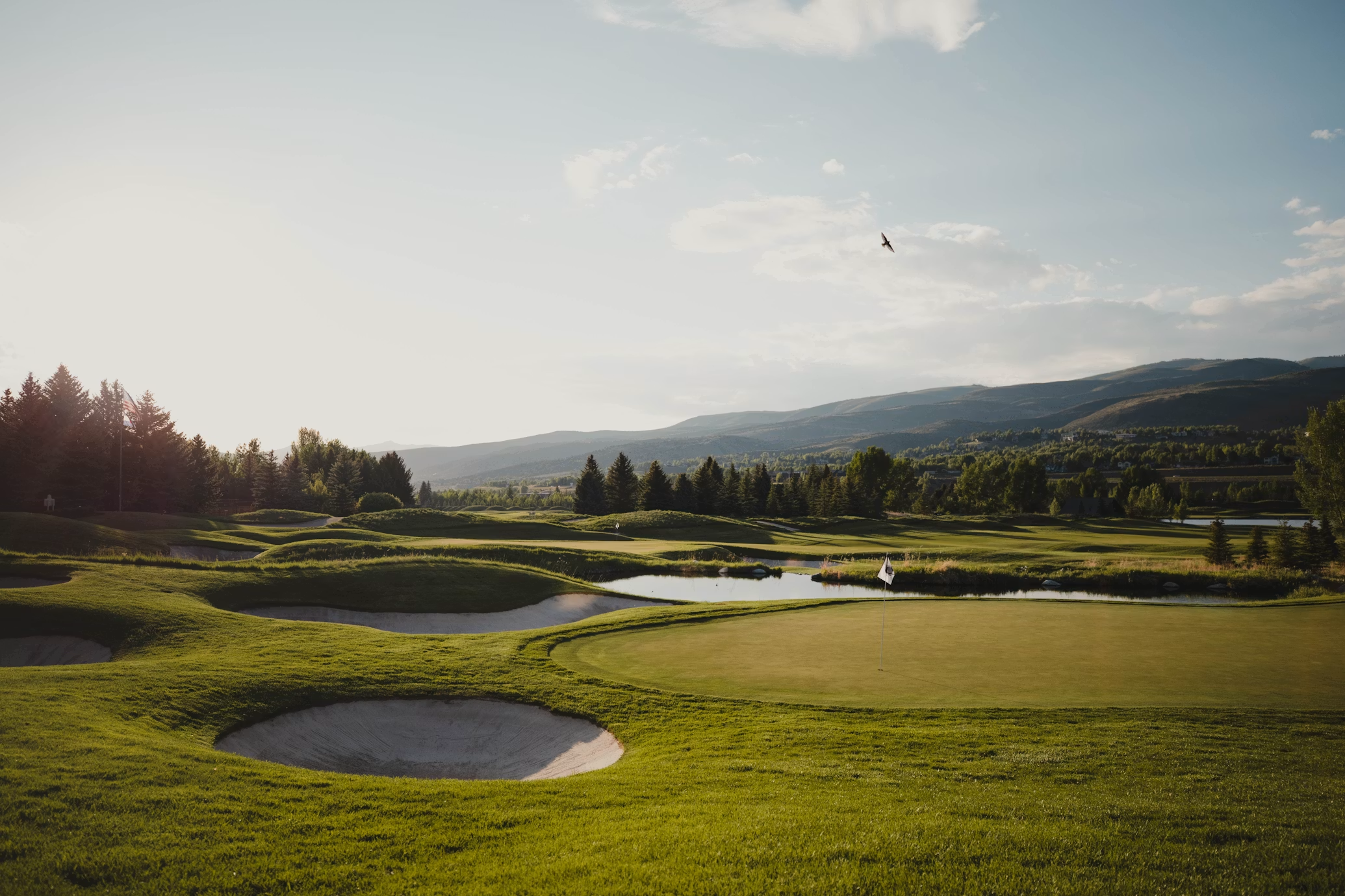 Mountain golf course with bunkers and pond at golden hour